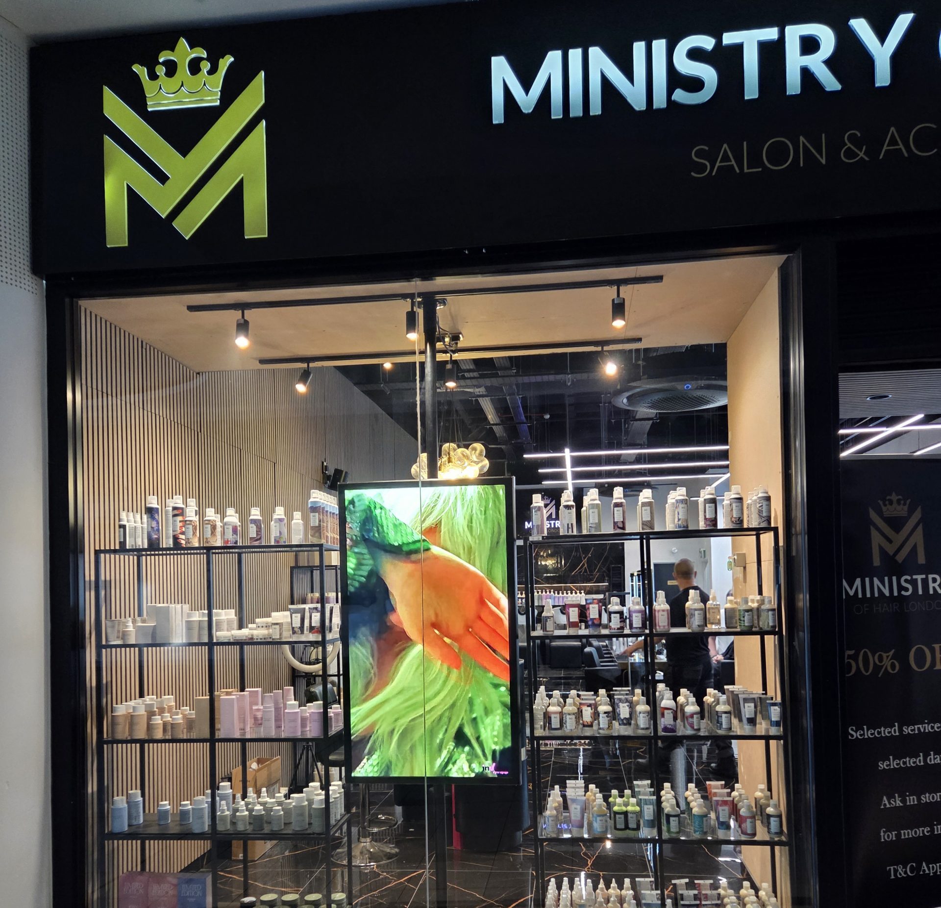 Window-mounted digital signage advertising hair and beauty services in a salon