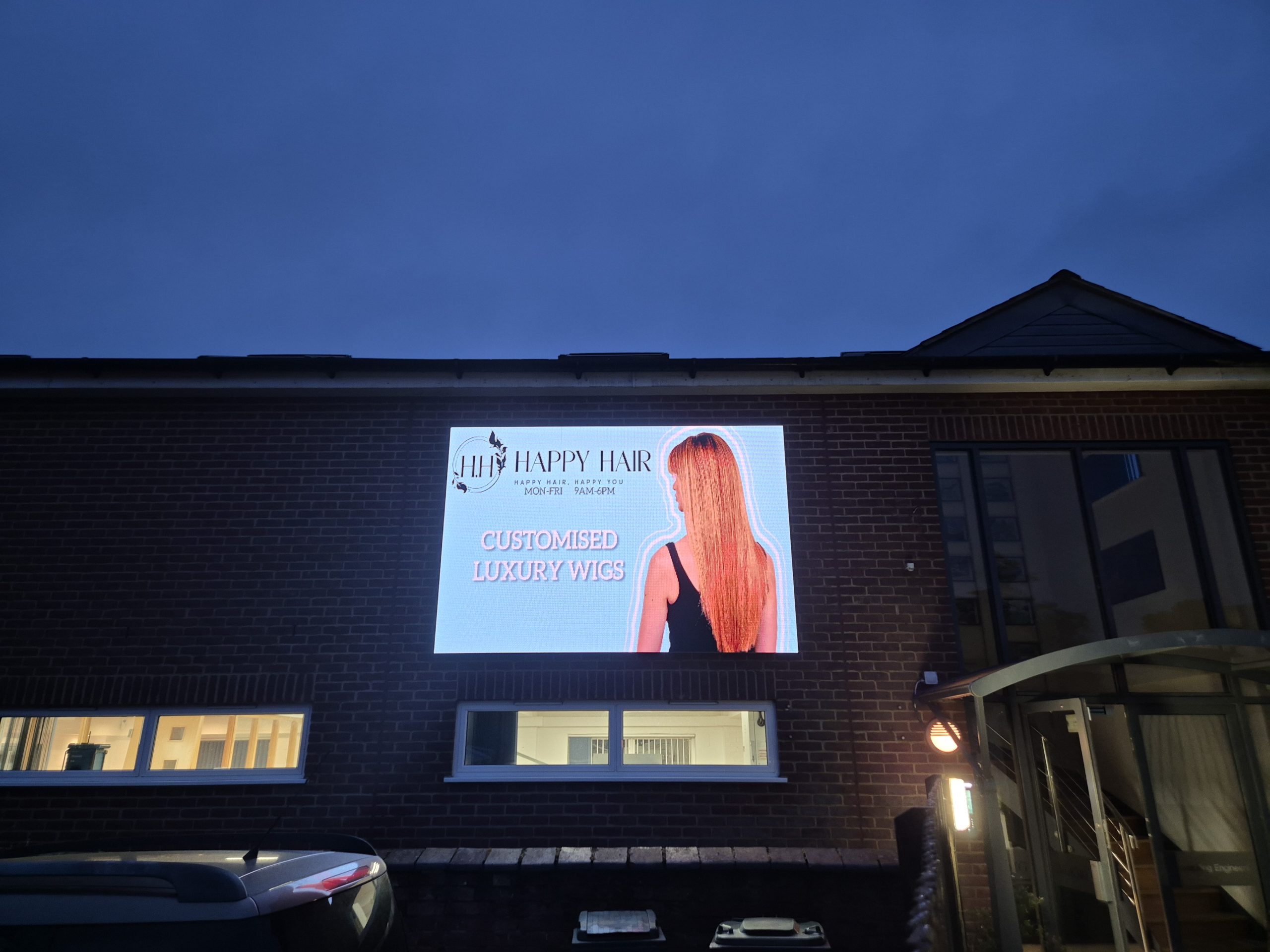 Outdoor digital signage screen used by a salon to advertise services and offers